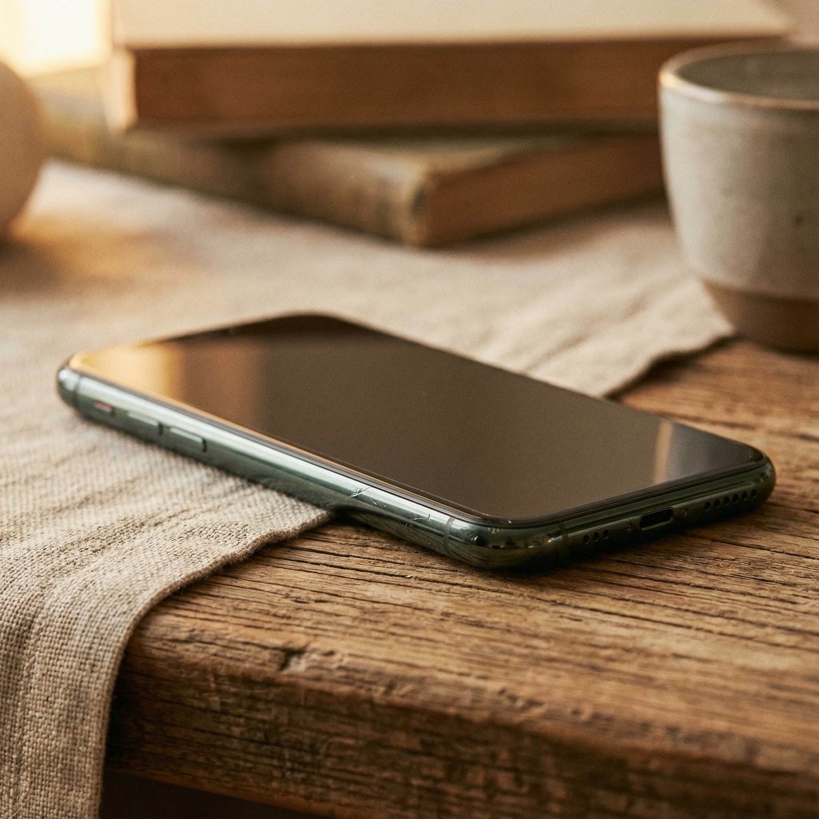 An iPhone 11 Pro with a subtle, elegant vintage filter, perhaps with a soft, warm glow, sitting on a textured background. The focus is on the phone, showing a classic yet slightly aged aesthetic. no visible text, aspect ratio 1:1, lifestyle photography