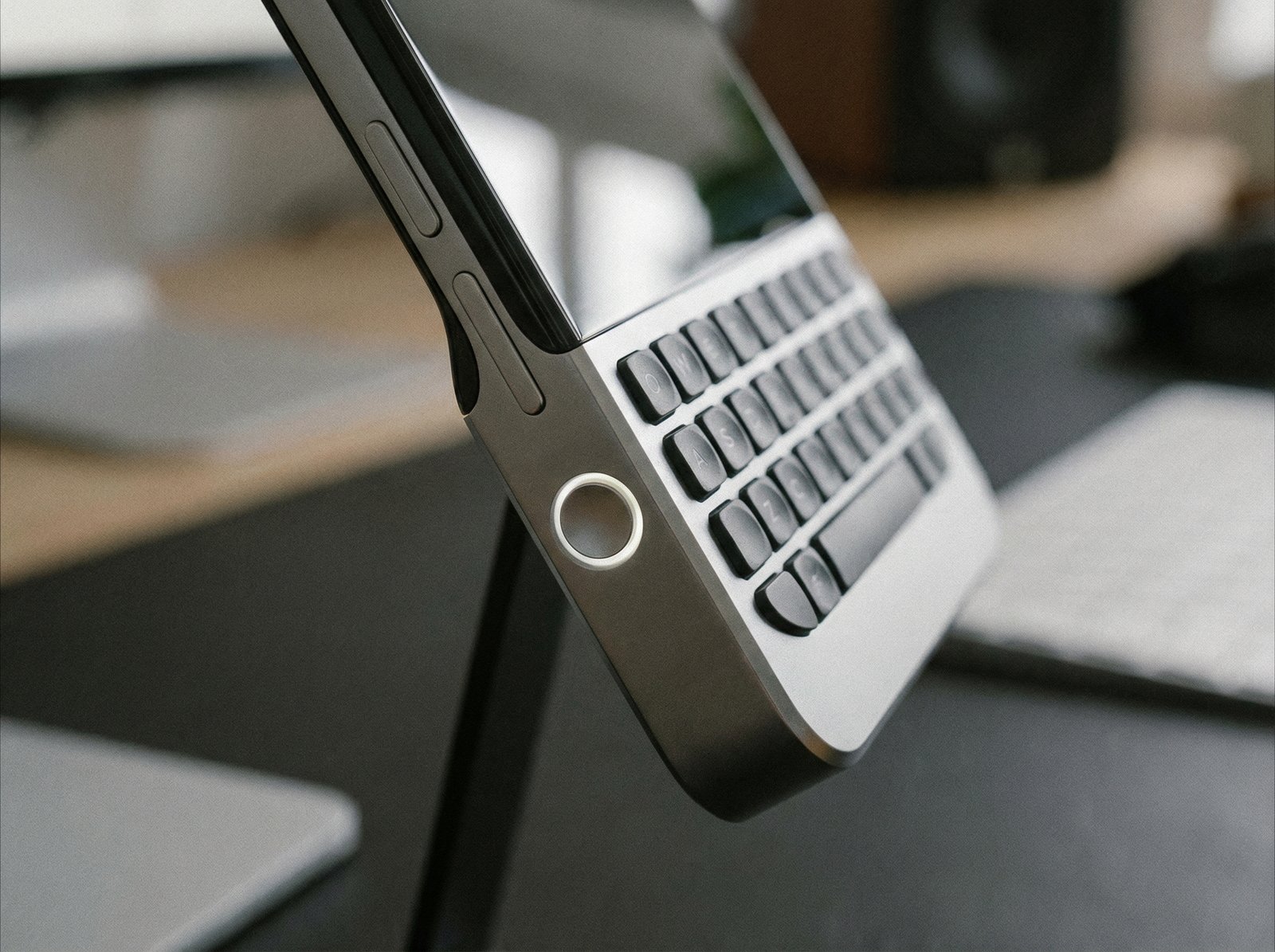 Close-up shot of a Clicks Communicator smartphone, focusing on its physical keyboard and the "Prompt Key" button on the side. The device is sleek and modern. No visible text. Aspect ratio 4:3.