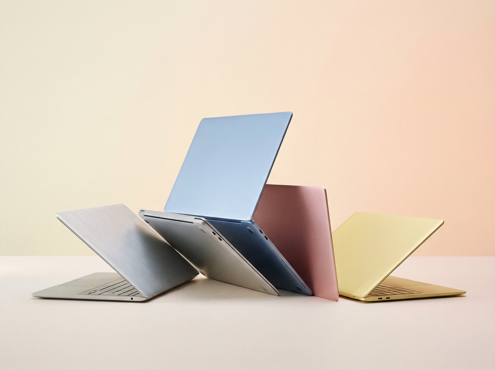 A series of thin, lightweight laptops in various bright, pastel colors like silver, blue, pink, and yellow, arranged elegantly against a minimalist, gradient background. Aspect ratio 4:3, no visible text.