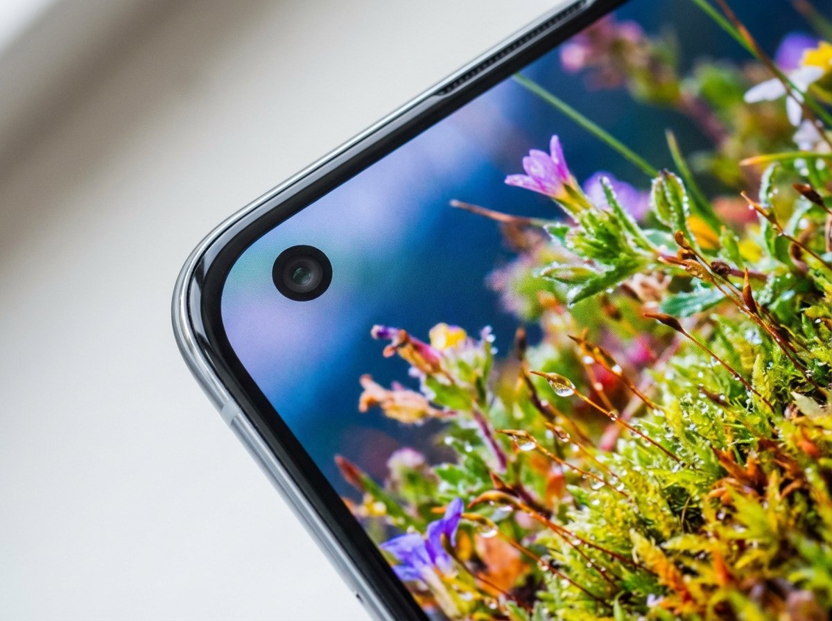 Close up of a smartphone corner with a small circular camera lens positioned in the upper left, clean bezel, vibrant screen display, 4:3