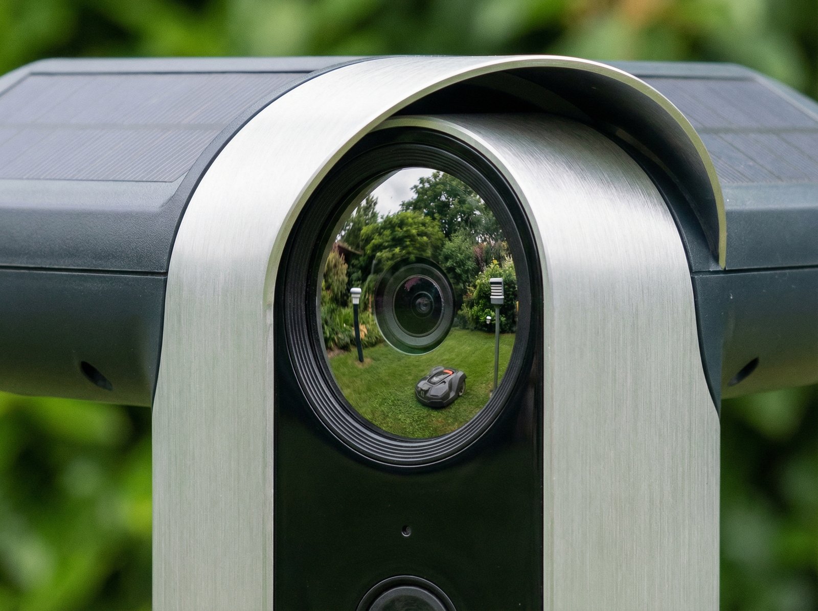 Close up of a sleek smart bird feeder camera lens showing reflection of a green garden, high tech garden equipment, no text, 4:3