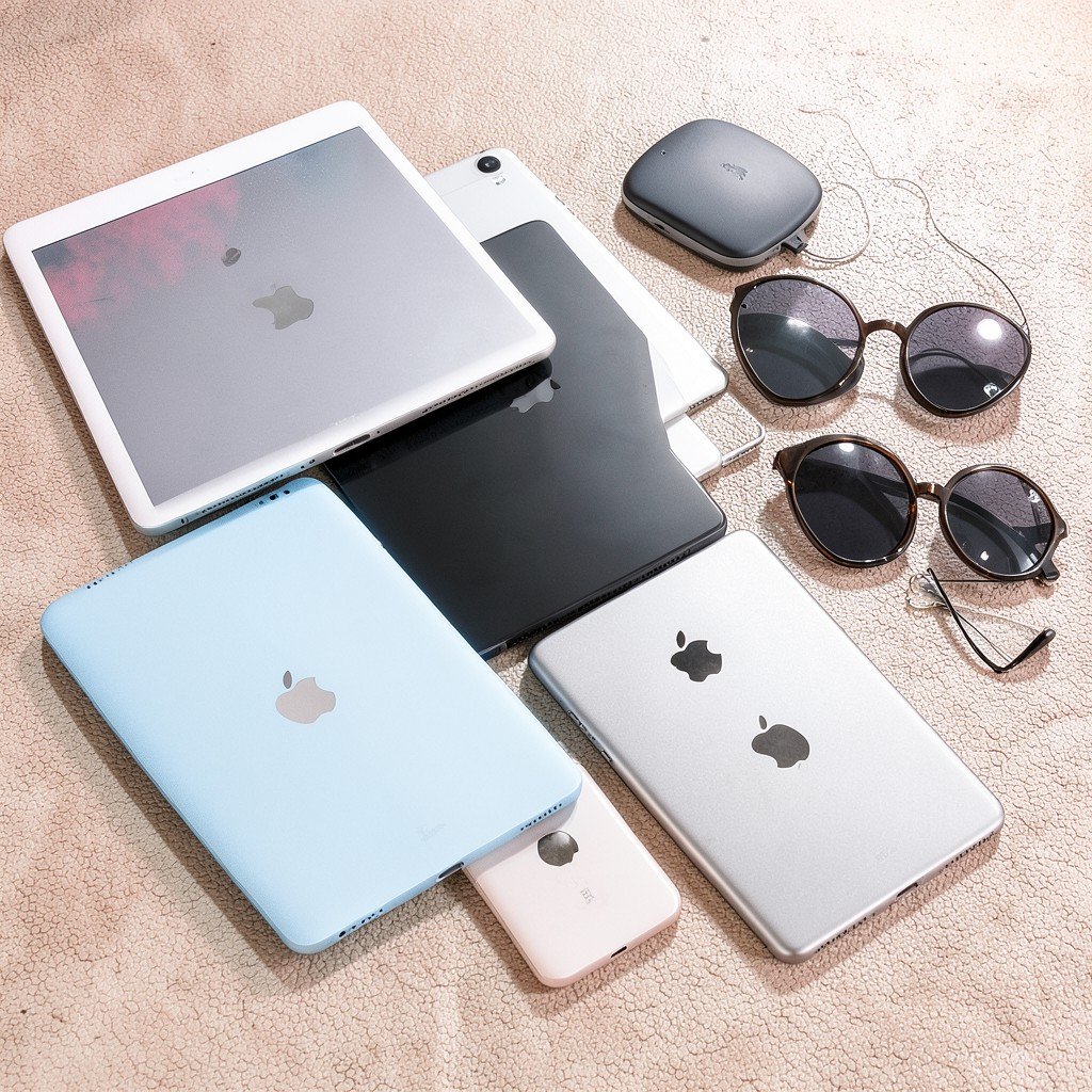 Various Apple devices including iPads and accessories arranged neatly on a textured surface, bright and balanced lighting, 4:3 aspect ratio.
